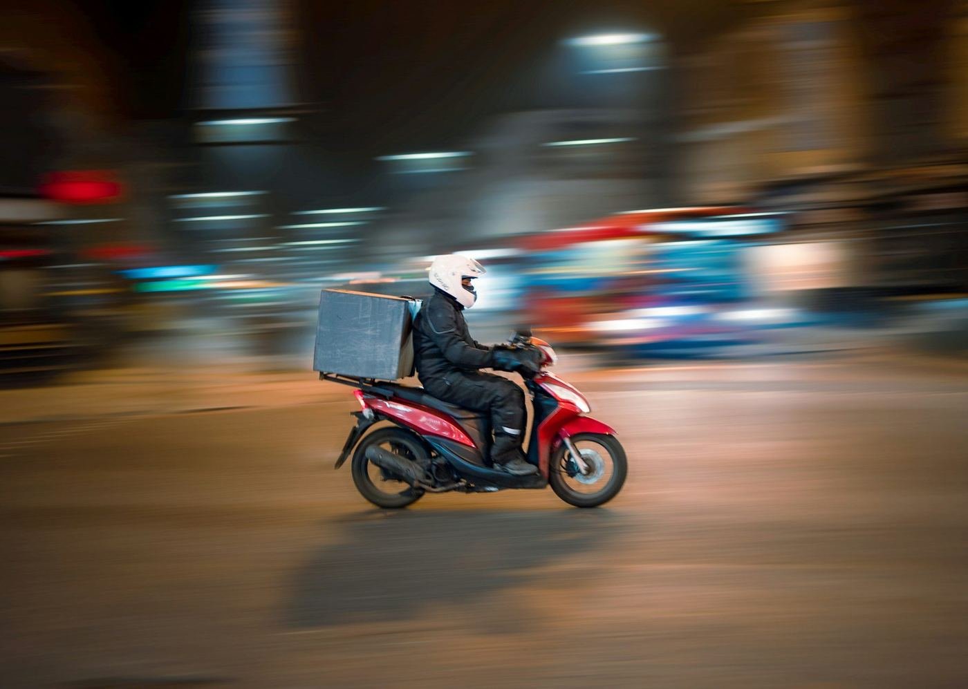 Delivery rider on a scooter heading out with an order at night