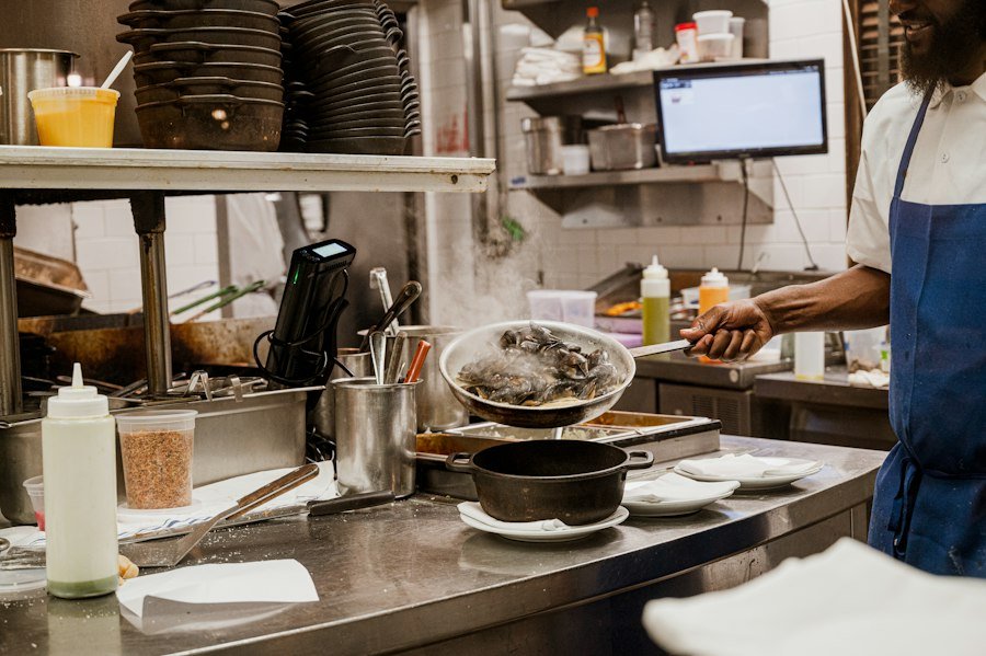 Busy cook line with pans, sauces and an order screen