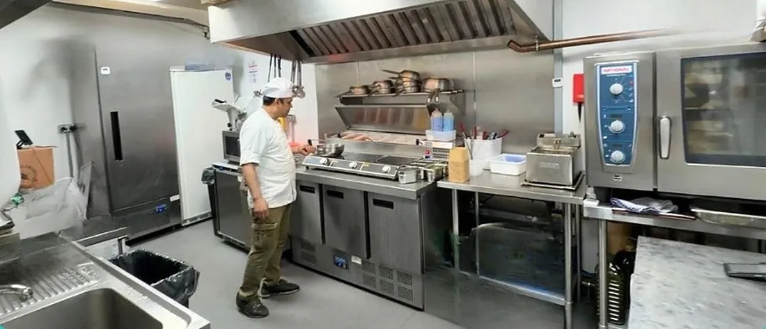 A fitted delivery kitchen at Ready Kitchen with a combi oven, prep counters and a chef at work