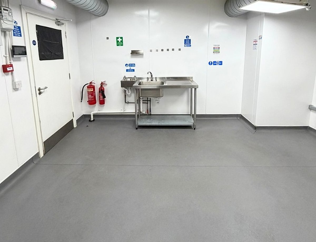 An empty Ready Kitchen unit with hygienic white walls, a non-slip floor and a prep sink, ready to fit out