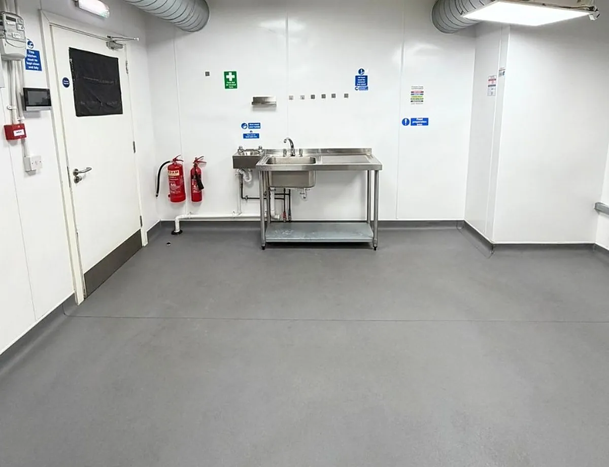 An empty Ready Kitchen unit with hygienic white walls, a non-slip floor and a prep sink, ready to fit out